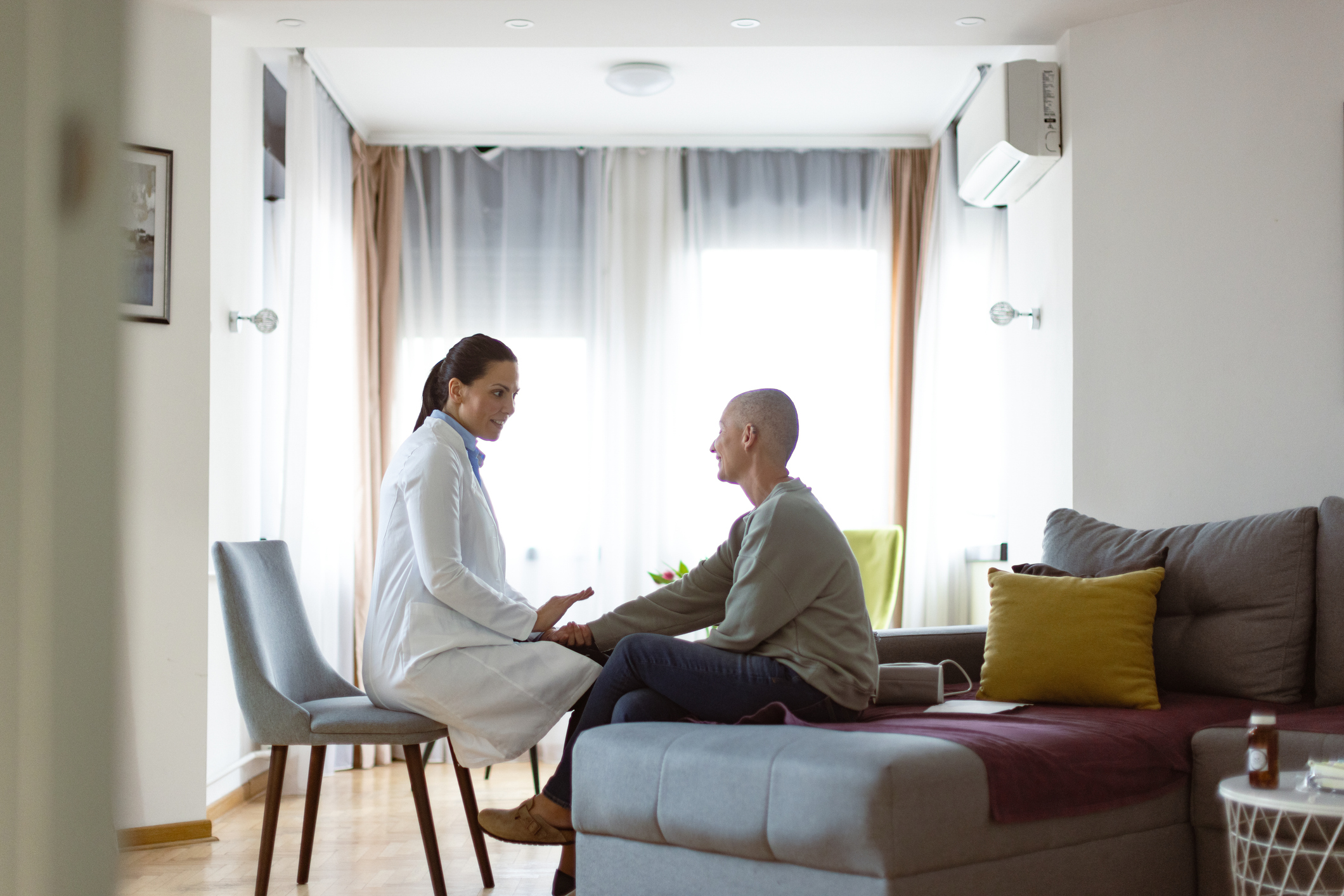 Na imagem, vemos uma médica e uma mulher sentada Ambos estão concentrados na conversa, e a expressão do médico parece ser de cuidado e preocupação. A paciente parece estar ouvindo atentamente, sua postura sugerindo confiança e uma abertura para receber as informações. A atmosfera parece ser de conforto e apoio durante este momento delicado de discussão sobre o tratamento do câncer.