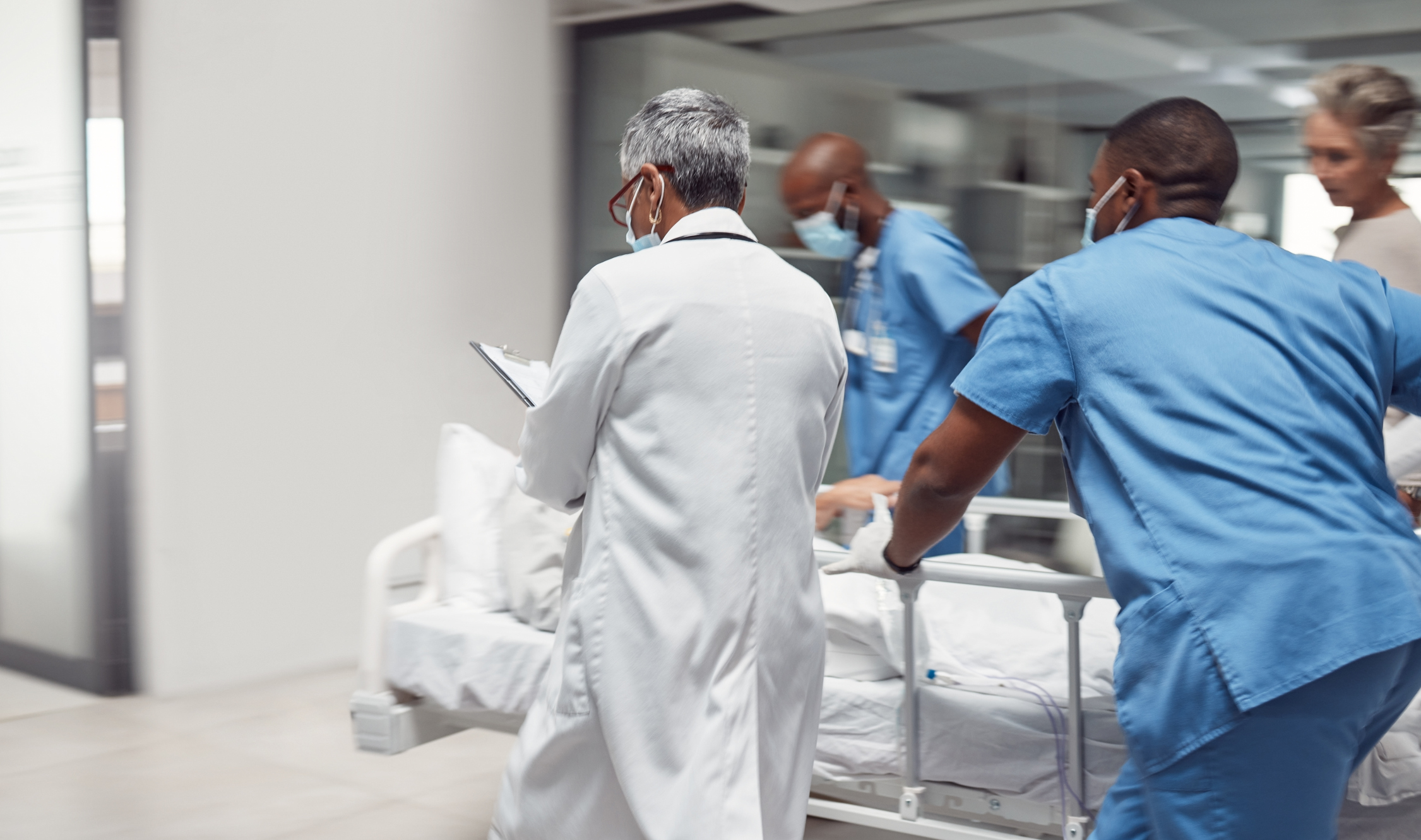 Ocupados, profissionais de saúde e médicos correm com paciente em maca, pronto para procedimento no hospital.